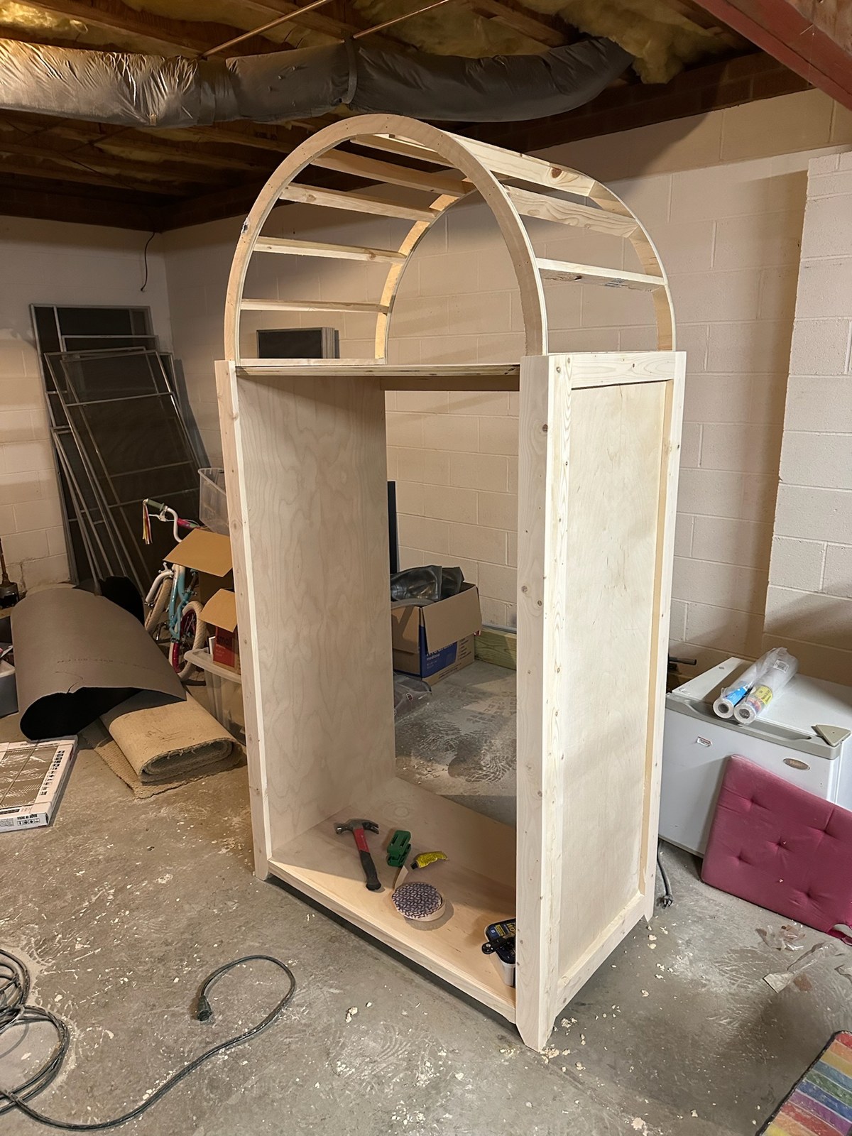 Unfinished armoire with curved ribs forming the arched top