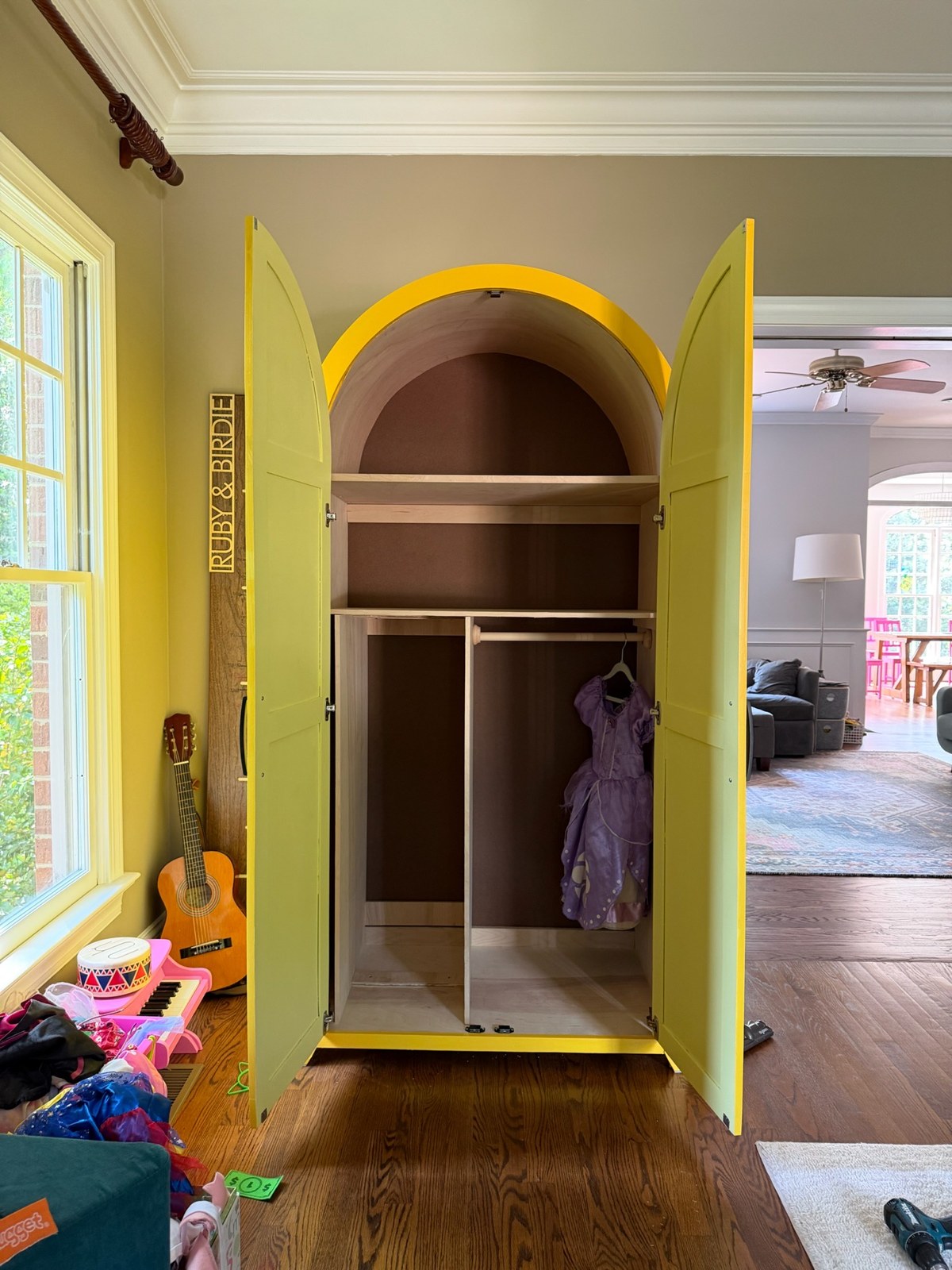 Yellow armoire with open doors, shelves, and hanging space