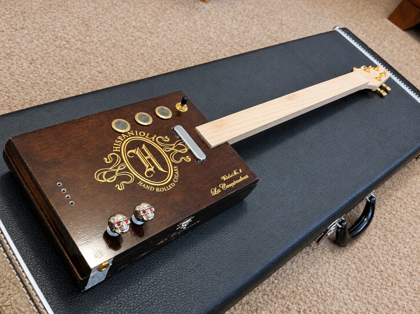 Cigar box guitar during assembly on a black instrument case